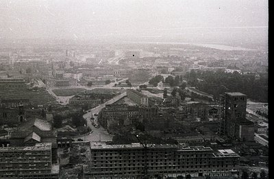 High-angle cityscape view. Extensive urban sprawl with a prominent central plaza & institutional buildings. Visible river in ...