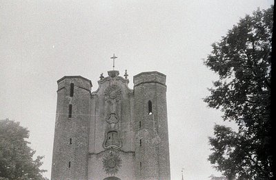Striking architectural facade of a stone building, likely a church or civic structure. Features three central towers with a d...