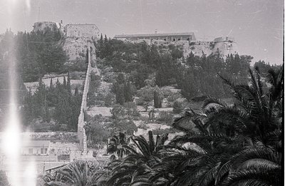 Overlooking the Black Sea, a fortified complex perches atop a steep, forested hill. A long stone wall snakes upwards, leading...