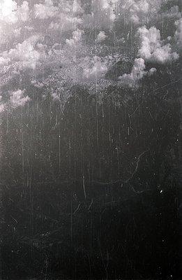 Striking, high-contrast monochrome print. Shows a sky with substantial cloud cover, heavily textured with visible dust and sc...