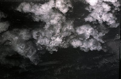 Striking black and white photograph depicting a dramatic, turbulent cloudscape. High contrast reveals textured cloud formatio...