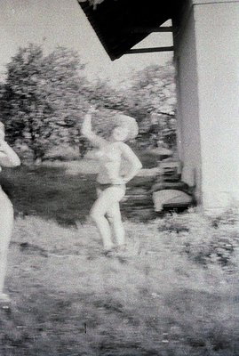 A candid snapshot captures a child mid-motion, seemingly dancing or playfully jumping. The scene is framed by a building over...