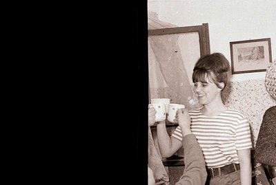A young woman with a short bob haircut smiles while participating in a tea ceremony. She wears a striped top and appears rela...
