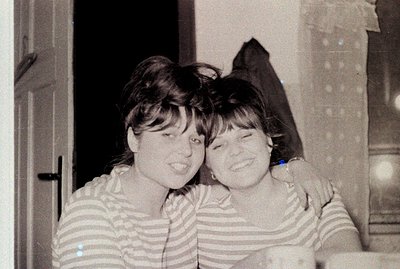 Two young women, dressed in matching striped tops, share a close, joyful embrace. The photograph, likely taken indoors near a...