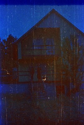 Striking blue tint photography depicting a two-story, wood-framed house with a prominent staircase. Visible details suggest a...