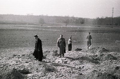 Group of figures observed on a sprawling, excavated earthworks site. Four individuals—likely engineers or supervisors—stand a...