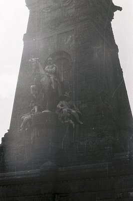 Close-up of a monumental stone sculpture depicting a seated, regal figure accompanied by allegorical figures. Part of a large...