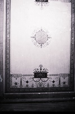 Ornate black & white wall panel featuring a central floral motif, decorative scrollwork, and a symmetrical border. Likely fro...