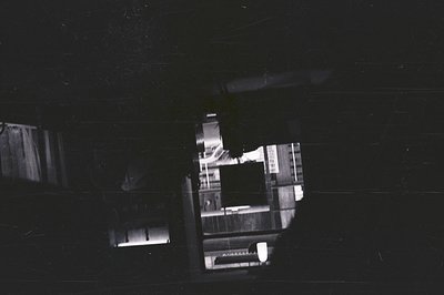 An intriguing view through an aperture, showcasing a street scene with blurred figures and vehicles. Architectural details ar...