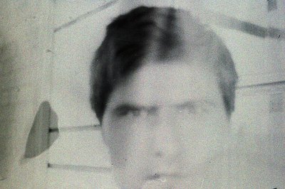 A vintage portrait of a man with short, neatly styled hair and a serious expression. Grainy black and white image, likely a p...