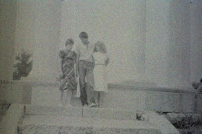 Three children stand on a stone ledge or staircase in what appears to be an architectural setting, possibly a courtyard or pu...