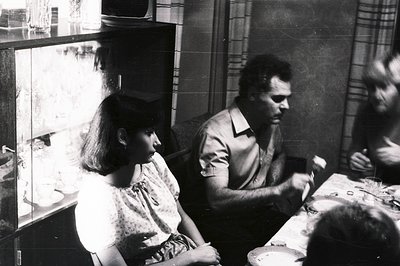 A monochromatic snapshot captures a candid moment: a young girl and a man seated at a table during what appears to be a meal....