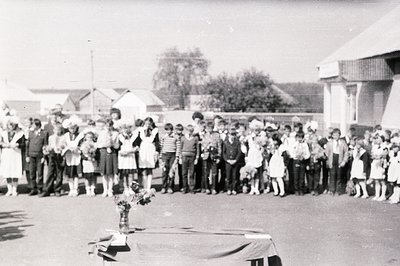 Group portrait of formally-dressed children, possibly a school class, gathered in a courtyard with residential buildings in t...