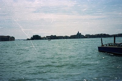 A view of the Venetian lagoon, featuring a classic wooden speedboat in the foreground and the island of San Giorgio Maggiore ...