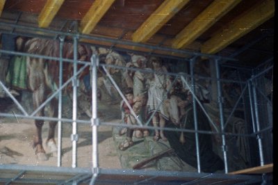Framed mural depicts figures, potentially biblical or historical, against a landscape with trees and possibly a body of water...