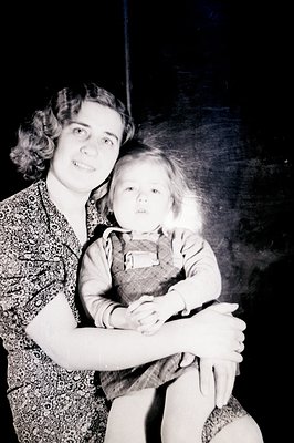 A young woman and child rest on a dark surface, seemingly posing for a studio portrait. The woman wears a patterned dress and...