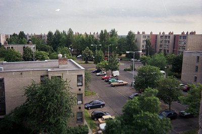 A view of a 1970s-era, high-rise apartment complex in Eastern Europe. Concrete architecture, visible parking lot, and densely...