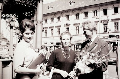 A formal portrait featuring a young woman in a short-sleeved dress, a middle-aged woman in a dark dress with a string of pear...