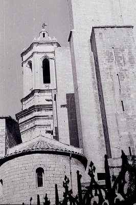 Stone church & bell tower with a tiered design & a cross atop. Arched windows are visible. Likely a European architectural st...