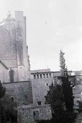 A tall, imposing stone church tower dominates this view, exhibiting Gothic architectural details. Adjacent structures show a ...