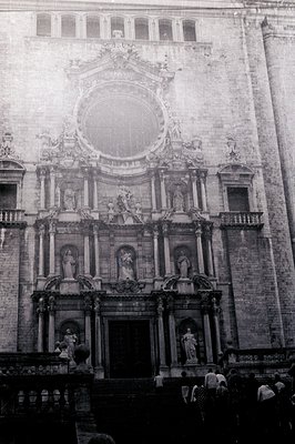 Monumental facade of a baroque-style cathedral features elaborate sculptural detailing, statues, and a central circular windo...