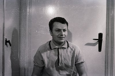 Close-up of a young man in a light-colored polo shirt, posing in front of a plain door. Appears to be a candid, possibly prom...