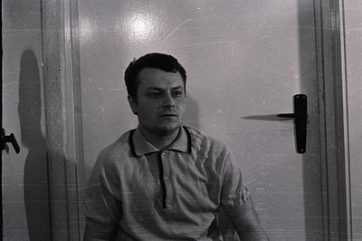 A portrait of a young man in a short-sleeved polo shirt. The photograph, exhibiting film grain and light flares, features a p...