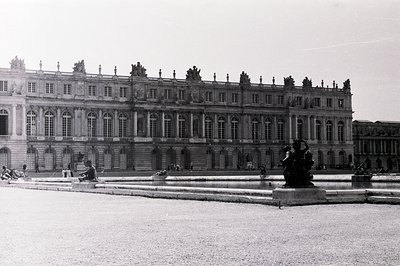 Ornate, symmetrical facade of the Palace of Versailles, France. Classical architecture features numerous windows, elaborate c...