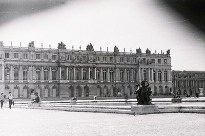Grand view of the Palace of Versailles, France, showcasing its elaborate Baroque architecture with tiered facades, numerous w...