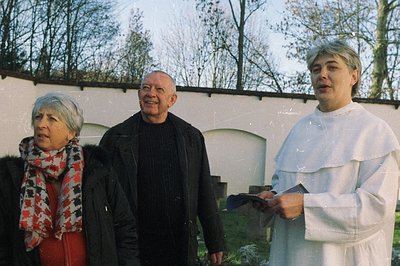 Formal portrait of a man in clerical garb delivering a speech to a couple. Architectural backdrop suggests an institutional s...