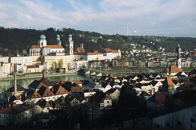 A panoramic view of the historic town of Passau, Germany, showcasing a riverfront cityscape with red-tiled roofs and the impr...