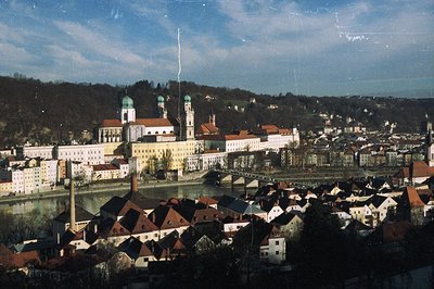 A panoramic view captures Passau, Germany. The Danube and Inn rivers converge, with the Dom St. Stephan, a Baroque cathedral,...
