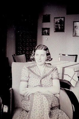 A portrait of a woman seated in an armchair, posed formally. She wears a patterned dress with a V-neckline, typical of the 19...