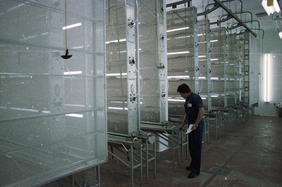 An industrial spray booth system, featuring multiple stainless steel panels suspended from overhead tracks. A worker in a dar...
