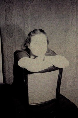 Here's a description of the photograph, following all provided guidelines: Ethereal portrait – a seated figure with arms cros...