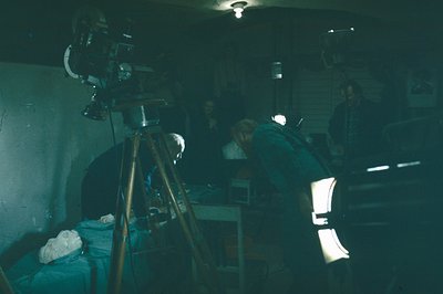 A patient lies under a camera rig, likely for a medical or scientific procedure, in what appears to be a basic, institutional...