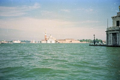 A long-shot view of Venice, Italy, showcasing San Giorgio Maggiore island & its bell tower across the lagoon. A stone pier oc...