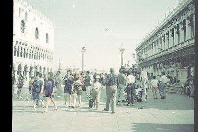 Wide view of St. Mark's Square in Venice, Italy. Crowded plaza features Basilica and Doge’s Palace. People in 1970s casual we...
