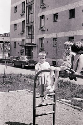Two children sit and pose on a metal playground structure, a typical example of mid-century recreational design. A Soviet-era...