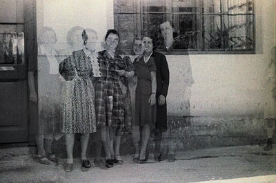 Four women stand formally outdoors, posed against a building’s exterior. Dresses with patterns and modest necklines suggest a...