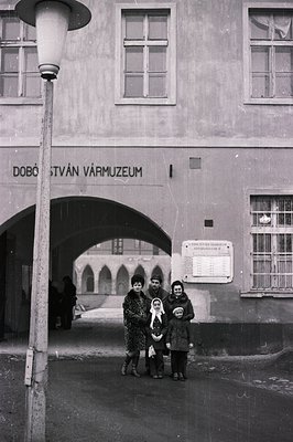 A family stands in a stone archway before a building with signage reading "Dobó István Vármúzeum." Likely 1960s or 70s, showi...