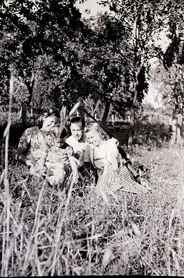 A family portrait, likely mid-1940s, shows a woman holding a young child, alongside a teenage boy. All three are nestled with...