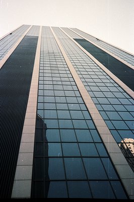Striking upward view of a modern skyscraper with a grid of reflective windows and prominent horizontal architectural details....