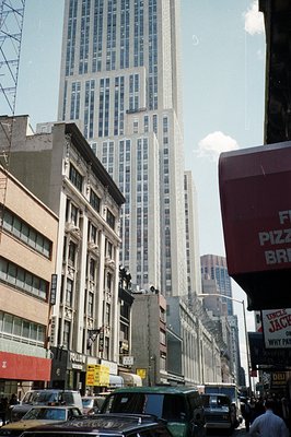 A street view in New York City, circa 1970s. Classic architecture lines the block, dwarfed by the Empire State Building risin...