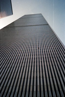 Striking low-angle view of a tall, modernist skyscraper, its facade defined by a grid of vertical and horizontal dark lines. ...