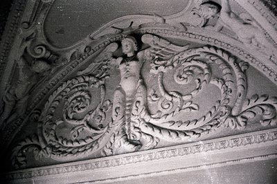 Detailed plasterwork of a female figure draped amongst scrolling foliage, likely part of a ceiling or wall relief. Classical ...
