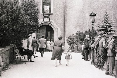 A group of men in military uniforms stand at attention along a paved courtyard, potentially awaiting inspection. A woman and ...