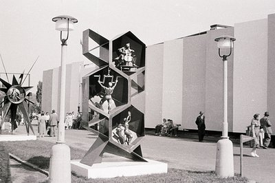 Geometric sculpture displaying figures in dynamic poses within hexagonal compartments. Likely an exhibition or public space; ...