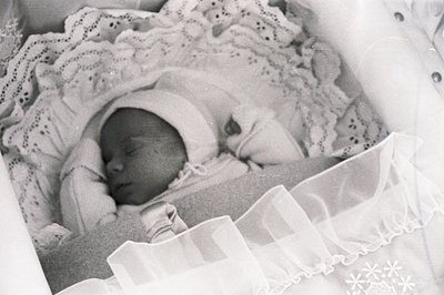 Close-up, black and white portrait of a sleeping infant, swaddled in delicate lace, suggesting a vintage or historical family...