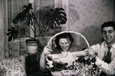 A couple joyfully displays a gift basket, potentially during a holiday celebration. The woman holds the basket with visible e...